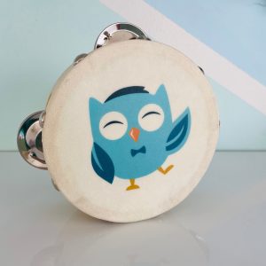 A close-up of a small wooden tambourine featuring an illustration of a blue owl