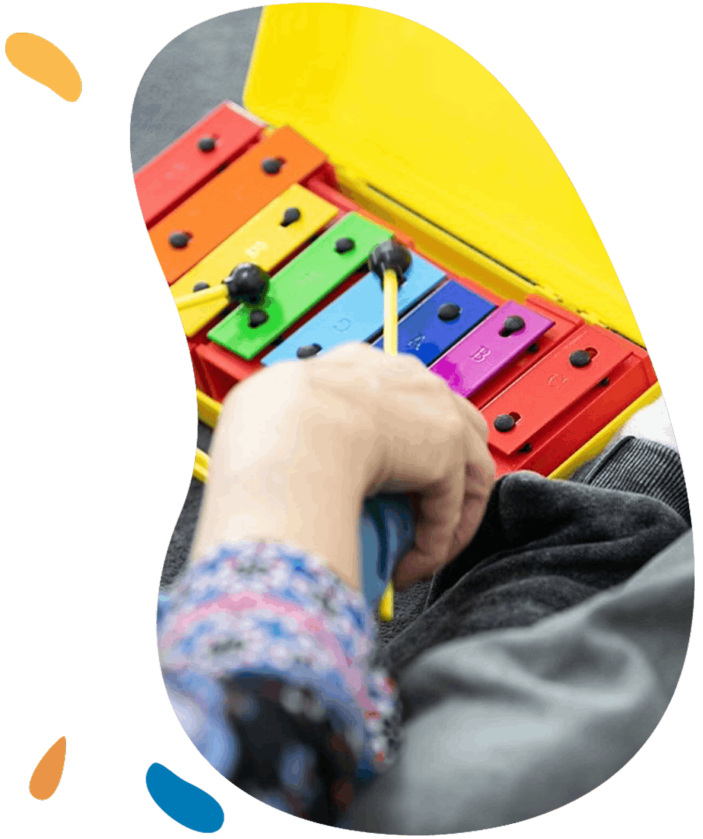 Child's hand playing a brightly colored glockenspiel