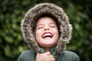 Child wearing a hood in winter laughing
